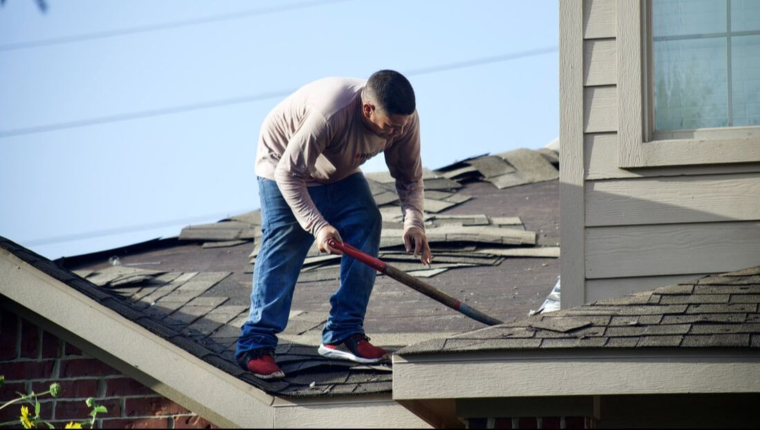 Roofer removing shingles for a roof replacement